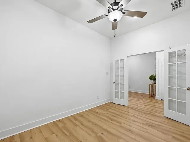 a view of empty room with wooden floor and ceiling fan