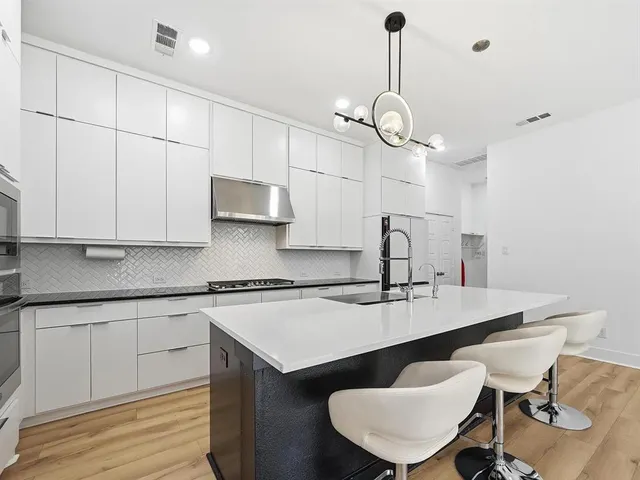 a very nice looking kitchen with granite countertop a stove a sink a dining table and chairs