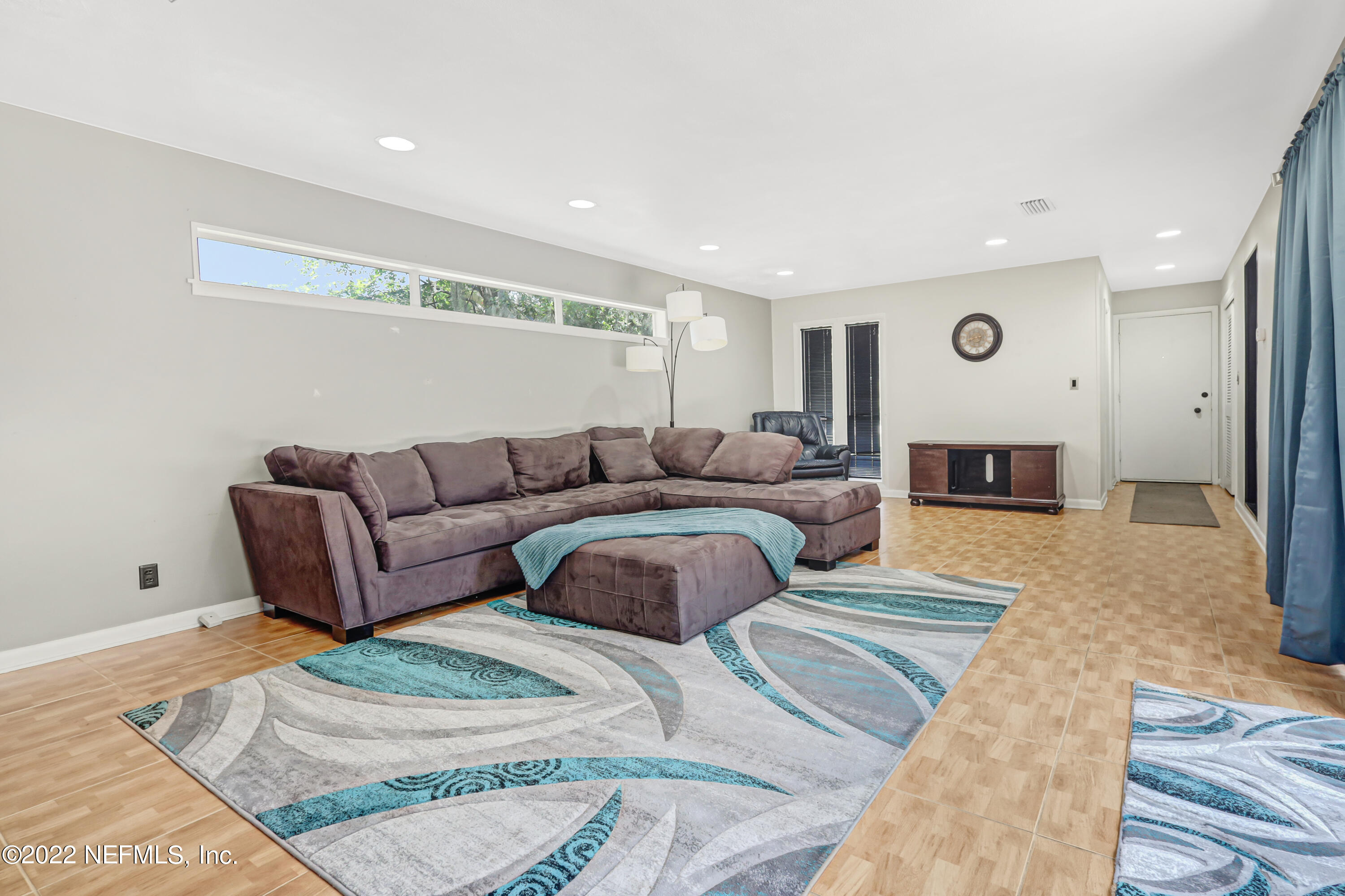 3955 Heidi Road Jacksonville, FL 32277 - Photo 7 of 43 a spacious bedroom with a bed a couch and a view of kitchen