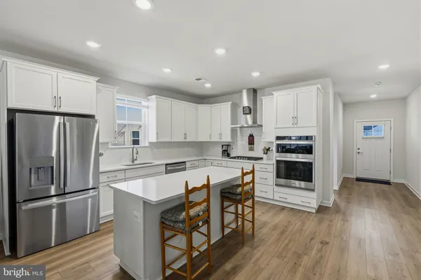 a large kitchen with kitchen island a stove a sink a oven a dining table and chairs