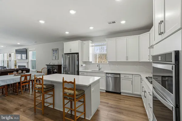 a large kitchen with cabinets chairs and wooden floor
