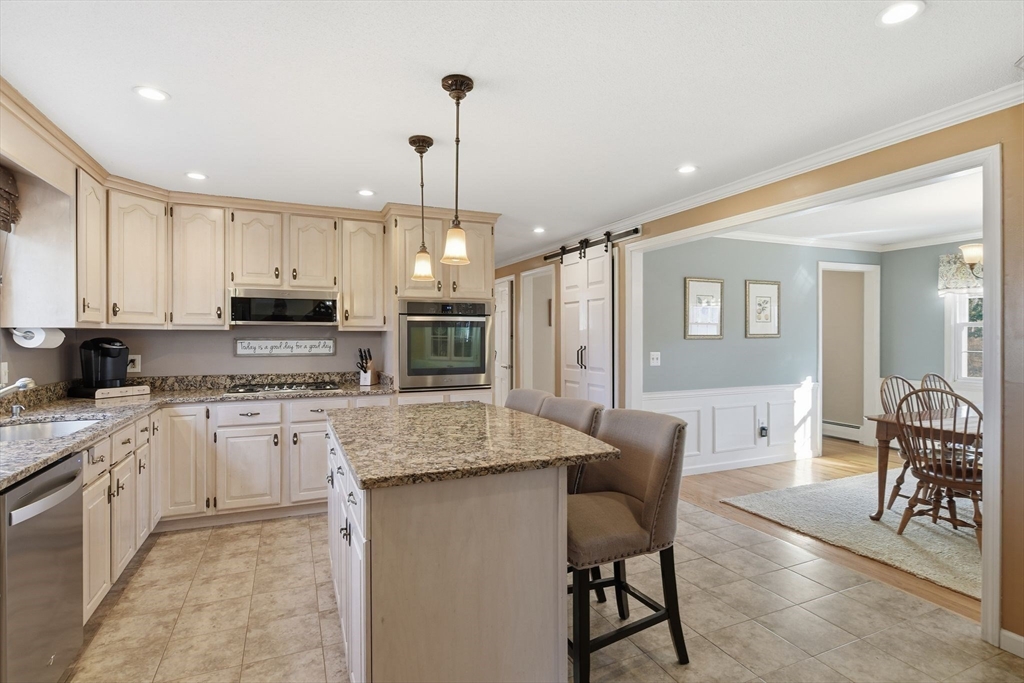 283 Forest Glen West Springfield, MA 01089 - Photo 9 of 40 a kitchen with stainless steel appliances granite countertop a stove top oven a sink dishwasher a dining table and chairs with wooden floor