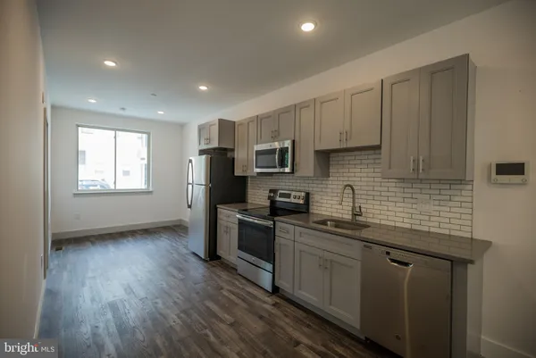 a kitchen with stainless steel appliances granite countertop wooden cabinets a sink a stove a refrigerator and dishwasher with wooden floor
