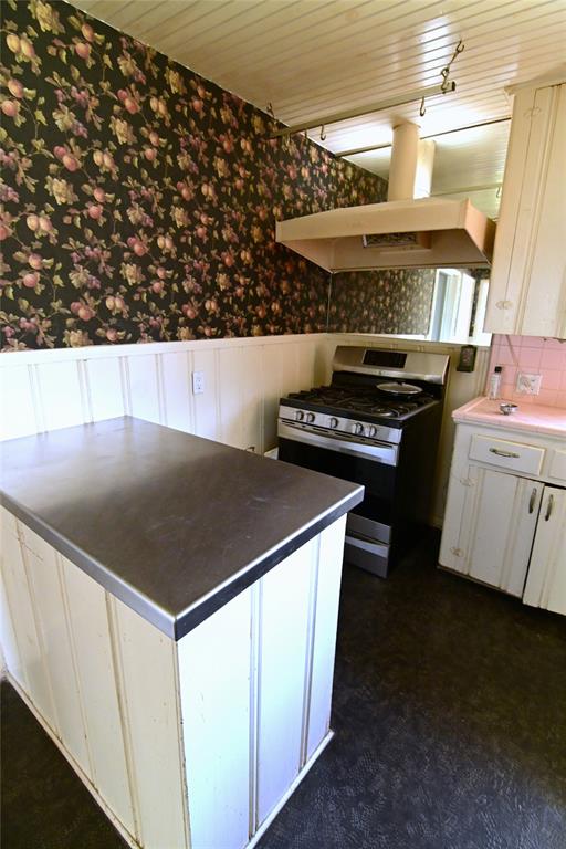 1916 Tierney Road Fort Worth, TX 76112 - Photo 8 of 12 Kitchen with stainless steel island gas stove, white cabinets, wainscoted wall, and exhaust hood