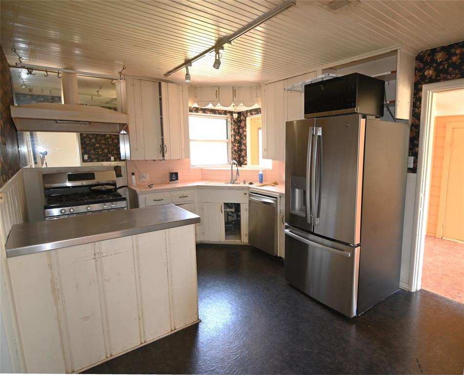 1916 Tierney Road Fort Worth, TX 76112 - Photo 9 of 12 Kitchen with appliances with stainless steel finishes, track lighting, white cabinets, light countertops, and wooden ceiling