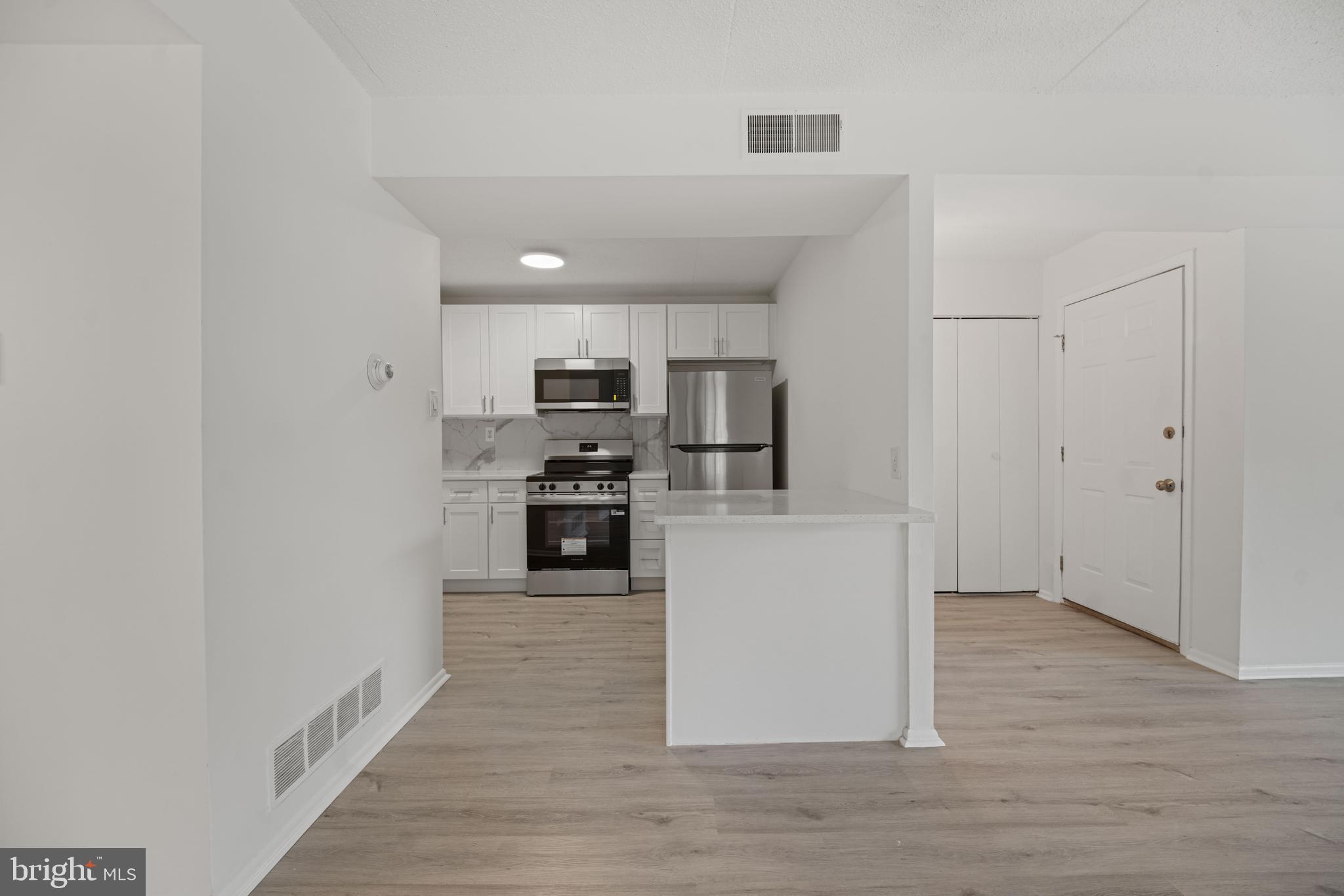 856 Putnam Boulevard, Unit 67A Wallingford, PA 19086 - Photo 7 of 26 a kitchen with wooden floor and electronic appliances