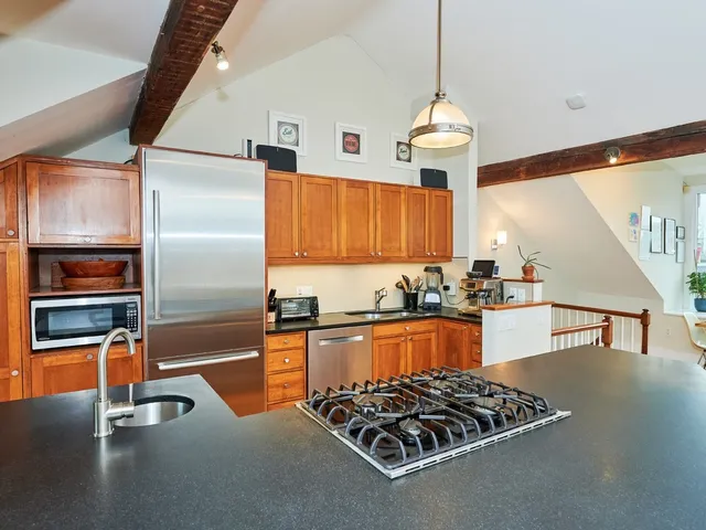 a kitchen with stainless steel appliances kitchen island granite countertop a table chairs and a wooden floor
