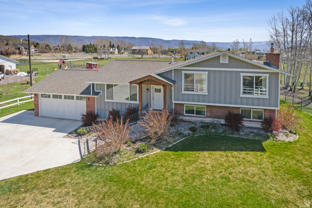 550 Pine Canyon Road Midway, UT 84049 - Photo 40 of 44 Split-level residence featuring a two-car garage with an overhead door, a brick and siding exterior, and a covered front entry with wood columns