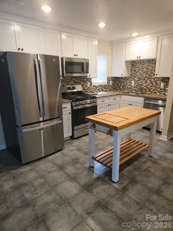 a kitchen with stainless steel appliances a refrigerator a stove a sink and a refrigerator