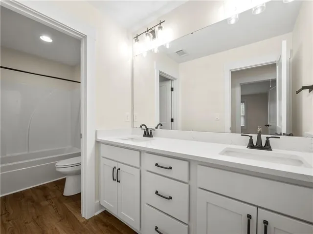 a bathroom with a double vanity sink toilet and shower