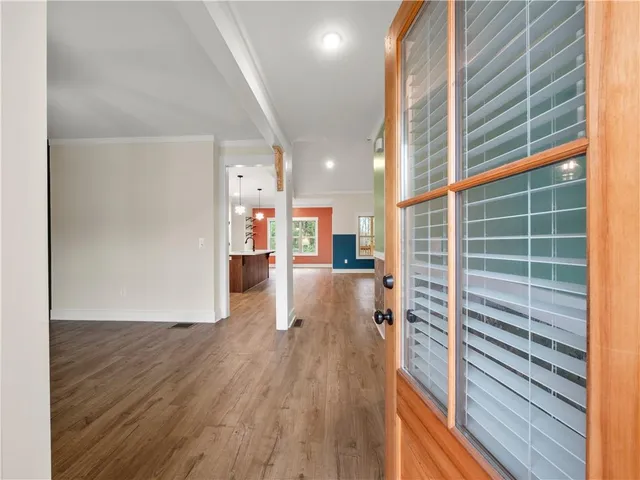 a view of a hallway with wooden floor and seating space