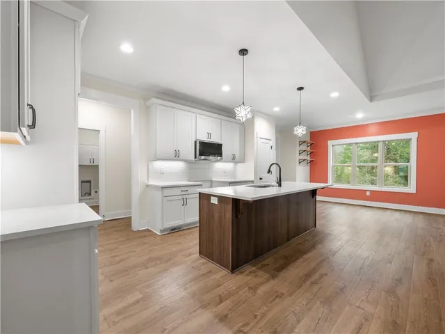 a large kitchen with a large counter top a sink stainless steel appliances and cabinets