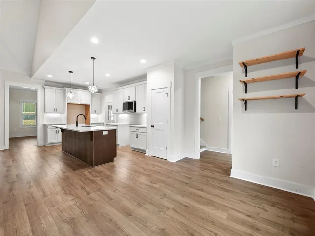 a large kitchen with cabinets wooden floor and a refrigerator