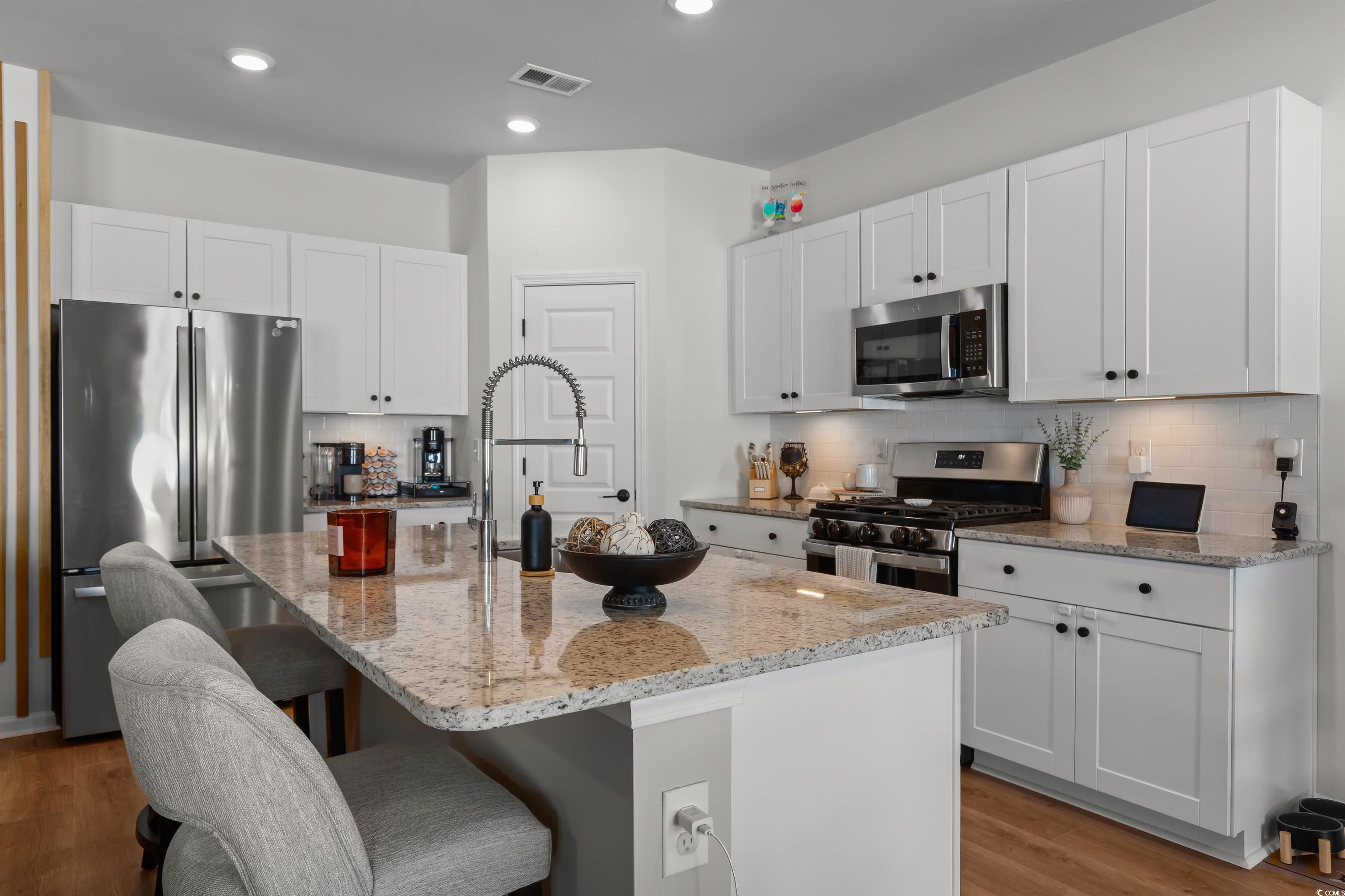 1067 Saltgrass Way Myrtle Beach, SC 29588 - Photo 21 of 40 Kitchen featuring decorative backsplash, light stone counters, white cabinetry, and recessed lighting