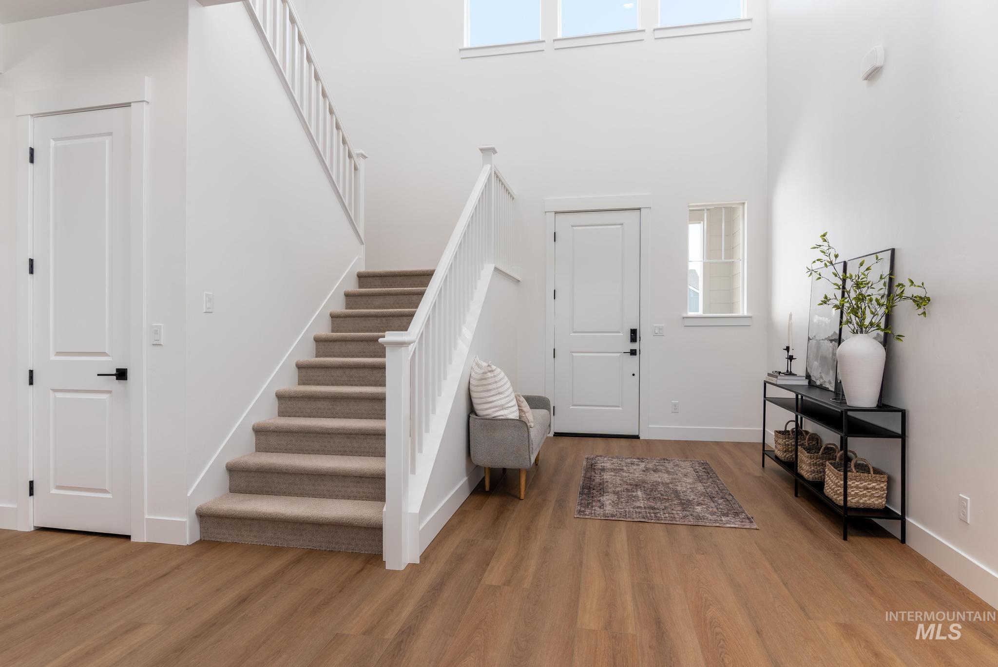 14703 Serenity Pt Street Caldwell, ID 83607 - Photo 4 of 45 Foyer with wood-finish flooring, a carpeted staircase with white balusters, and a double-height ceiling
