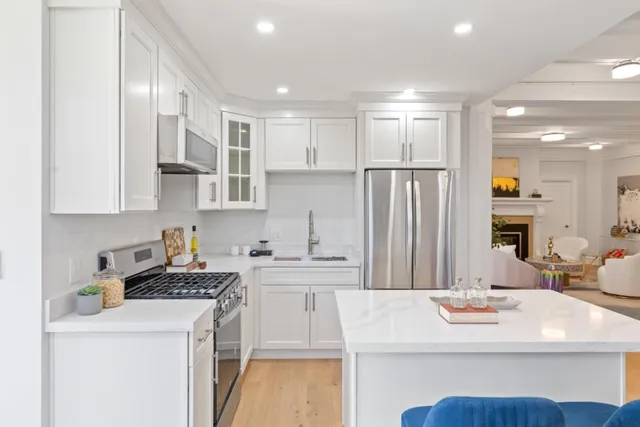 a kitchen with a sink a stove a refrigerator and white cabinets