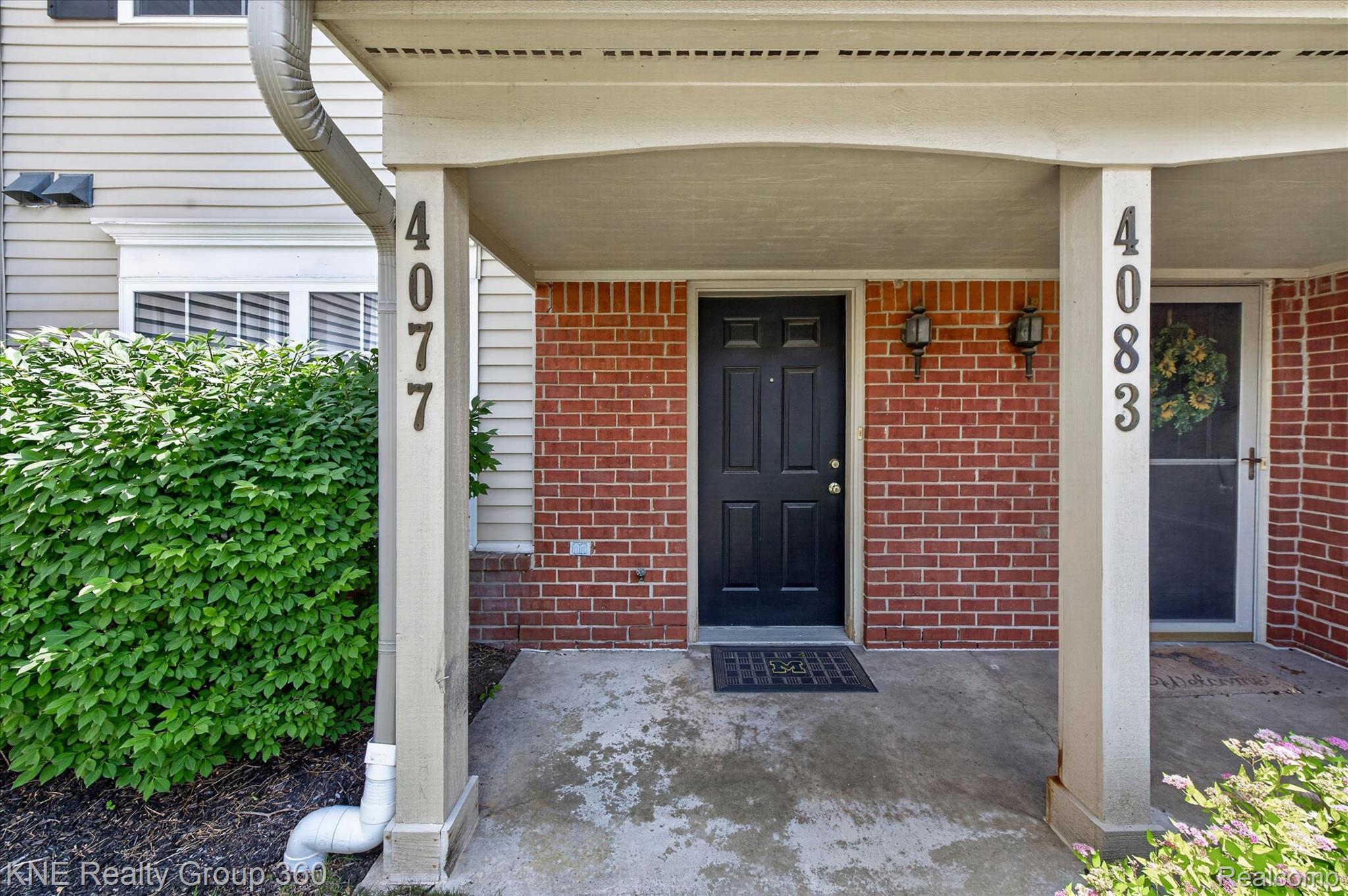 4077 Berkeley Avenue Canton, MI 48188 - Photo 5 of 32 Brick facade entry with a dark panel door, covered concrete porch, and twin exterior wall lanterns