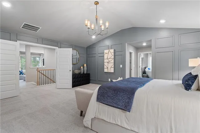 a spacious bedroom with a large bed a chandelier a mirror and couches