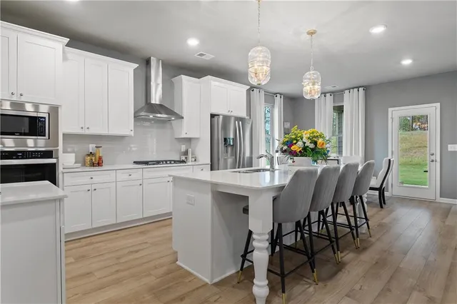 a kitchen with stainless steel appliances kitchen island granite countertop a table chairs and a refrigerator