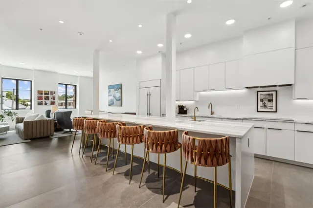 a kitchen with stainless steel appliances granite countertop lots of white cabinets and chairs