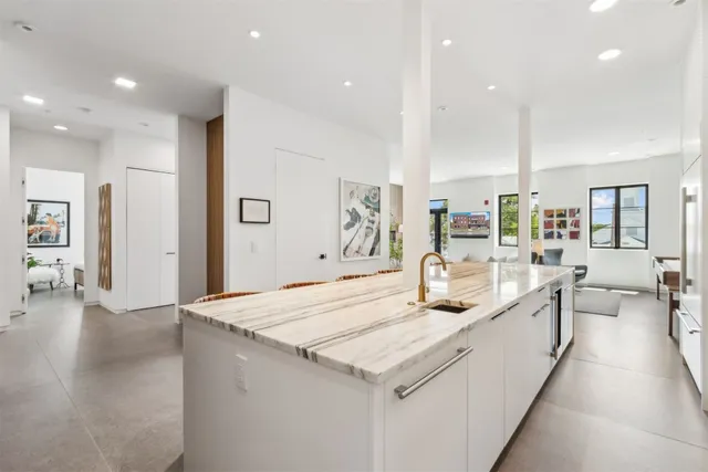 a large kitchen with kitchen island a large counter top and stainless steel appliances