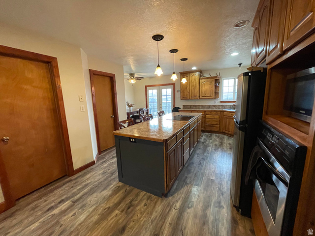 333 Lago Liberty Road Grace, ID 83241 - Photo 27 of 35 Kitchen with stainless steel appliances, a textured ceiling, a kitchen island, dark wood-type flooring, and pendant lighting