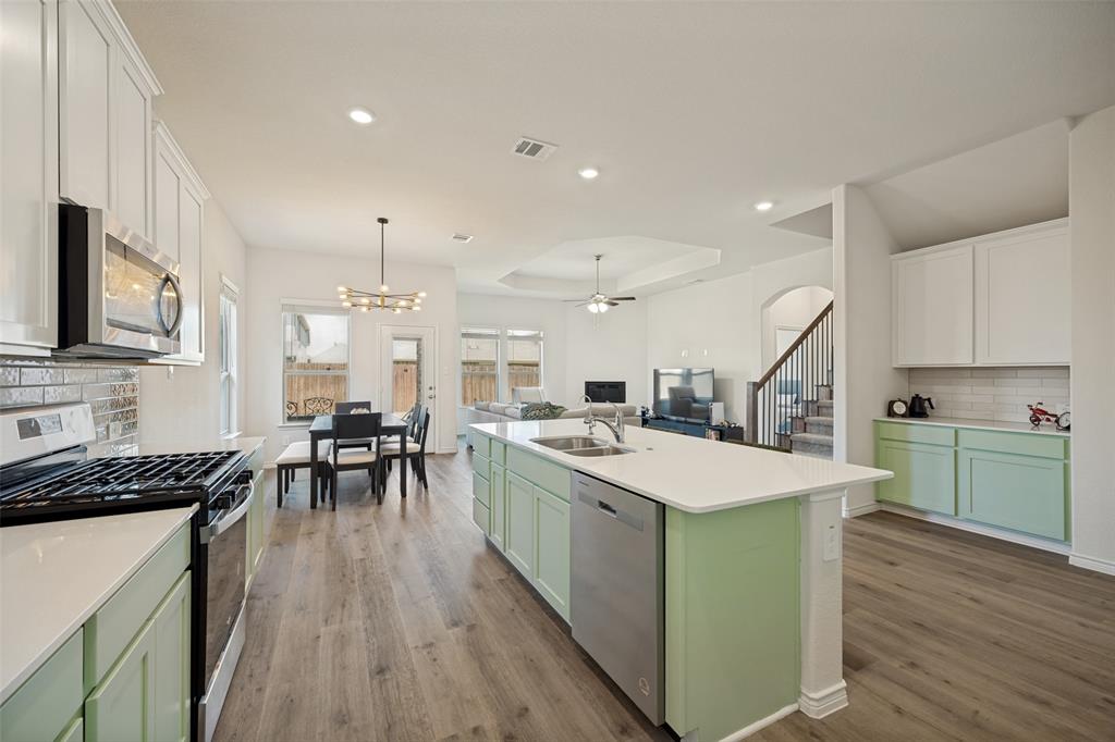 3816 Blacksmith Road Aubrey, TX 76227 - Photo 6 of 30 Spacious kitchen featuring an expansive island, stainless steel appliances, white countertops, and wood-finish flooring