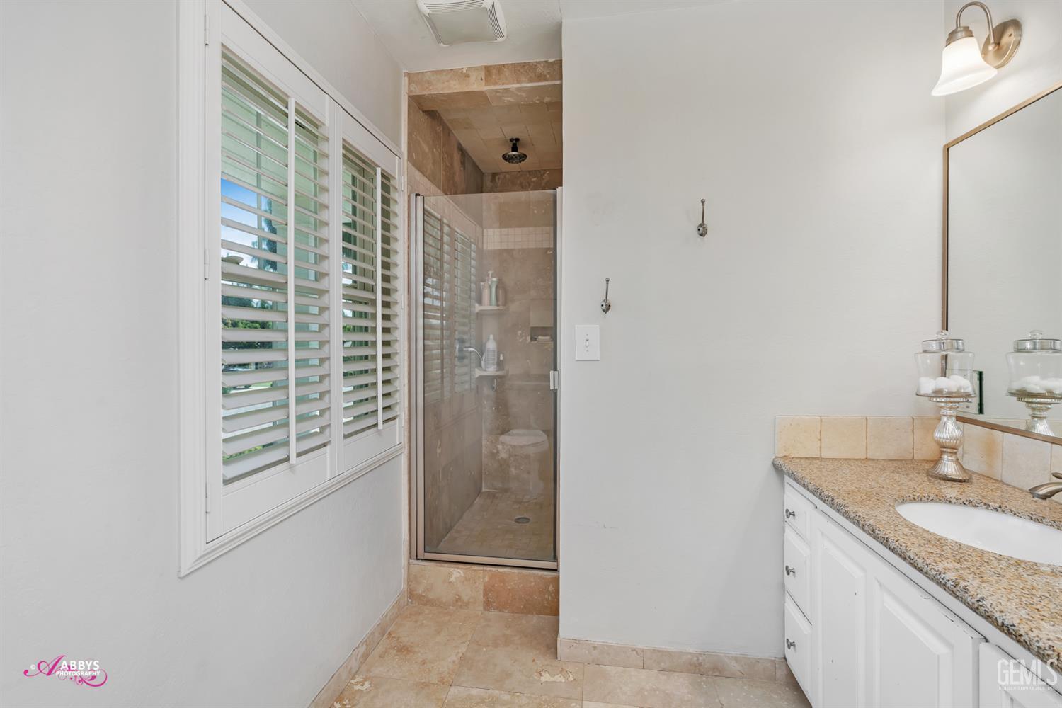 Undisclosed Address Bakersfield, CA 93309 - Photo 22 of 30 a bathroom with a granite countertop sink a mirror and shower