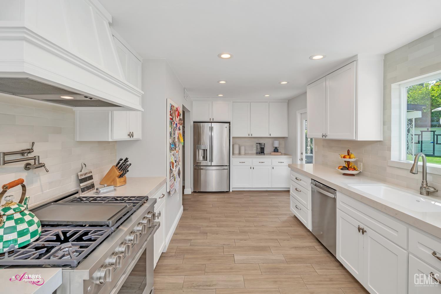 Undisclosed Address Bakersfield, CA 93309 - Photo 10 of 30 a kitchen with stainless steel appliances granite countertop a stove top oven a sink a refrigerator and white cabinets with wooden floor