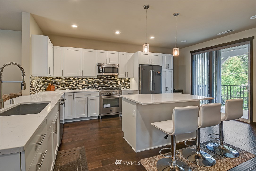 22810 23rd Avenue Southeast, Unit 2 Bothell, WA 98021 - Photo 5 of 16 a kitchen with kitchen island a sink stove and white cabinets