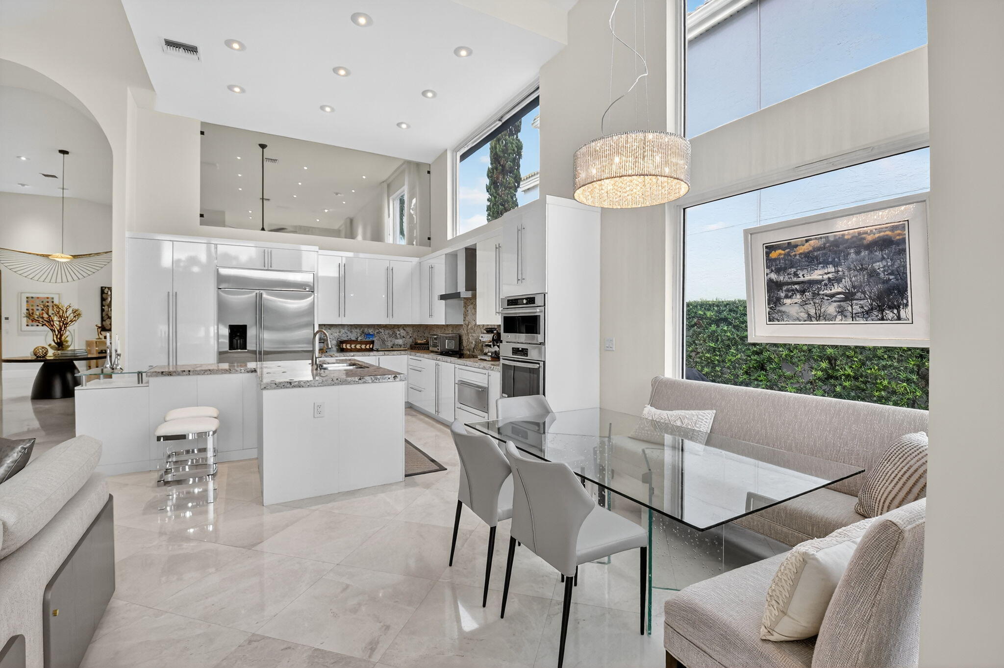 2563 Northwest 63rd Street Boca Raton, FL 33496 - Photo 17 of 65 a kitchen with stainless steel appliances kitchen island granite countertop a table chairs and a refrigerator