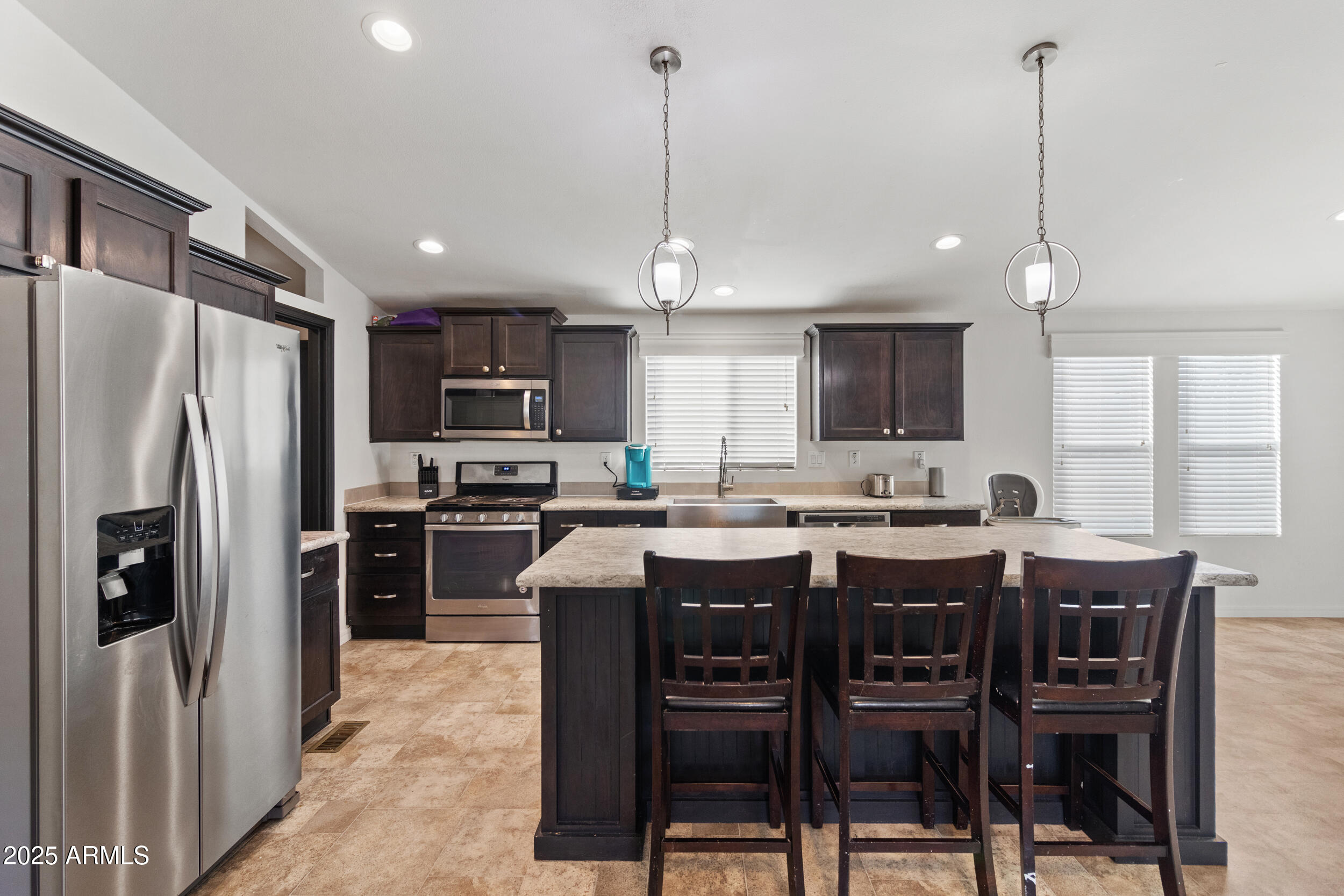 a kitchen with stainless steel appliances granite countertop a table chairs sink refrigerator and microwave