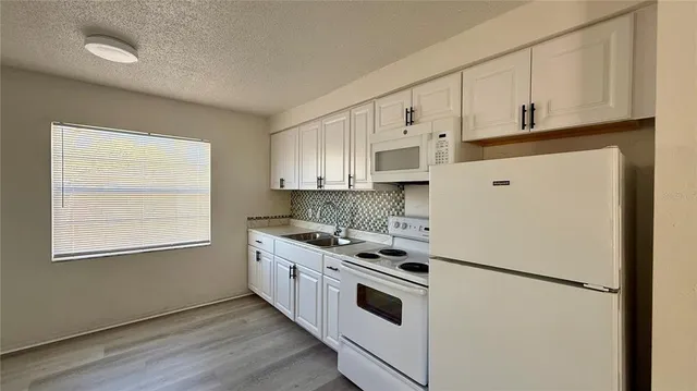 a kitchen with granite countertop white cabinets and white appliances