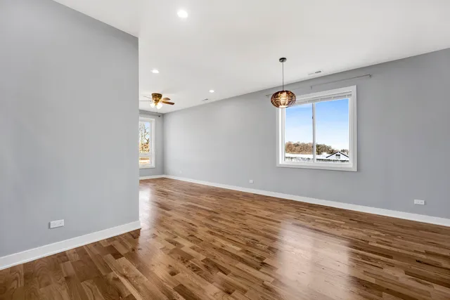 a view of empty room with wooden floor and ceiling fan