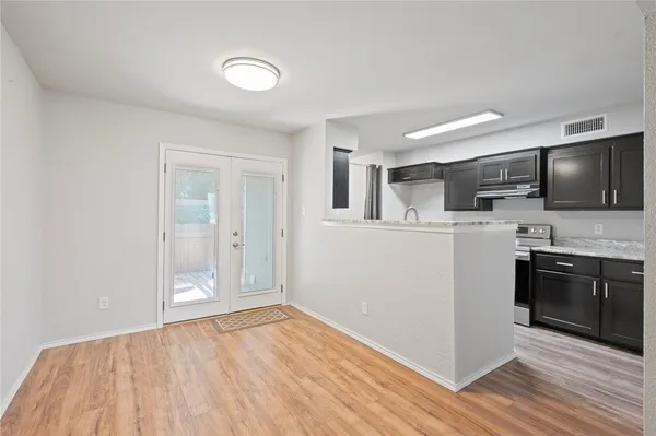 an empty room with wooden floor fan and windows