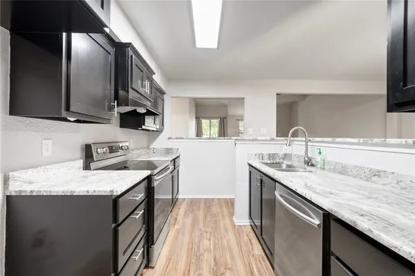 a kitchen with granite countertop stainless steel appliances a sink stove top oven and cabinets