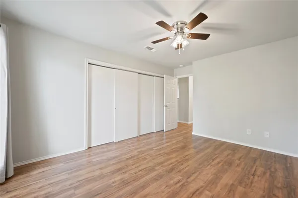 an empty room with wooden floor and ceiling fan