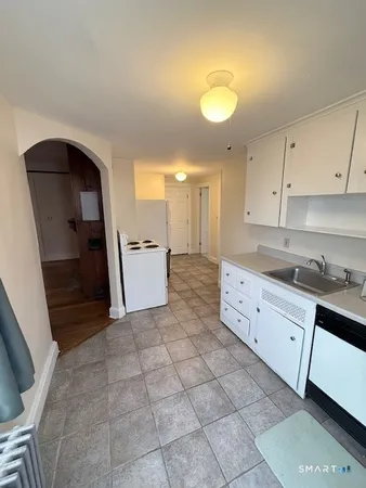 a kitchen with granite countertop a sink a stove a refrigerator and white cabinets