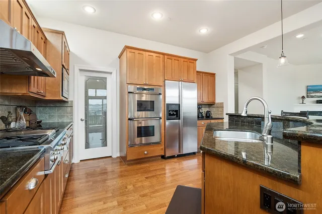 a kitchen with stainless steel appliances granite countertop a sink refrigerator and cabinets