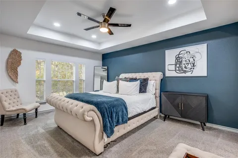 a spacious bedroom with a bed painting on wall and a large window