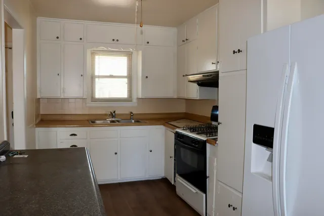 a kitchen with granite countertop a stove sink and cabinets