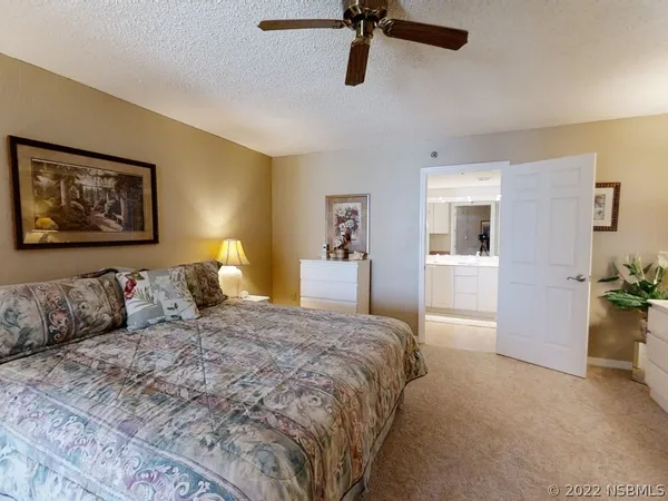 a spacious bedroom with a bed a couch and a chandelier