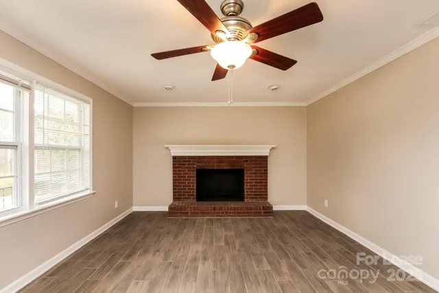 a view of an empty room with window and wooden floor