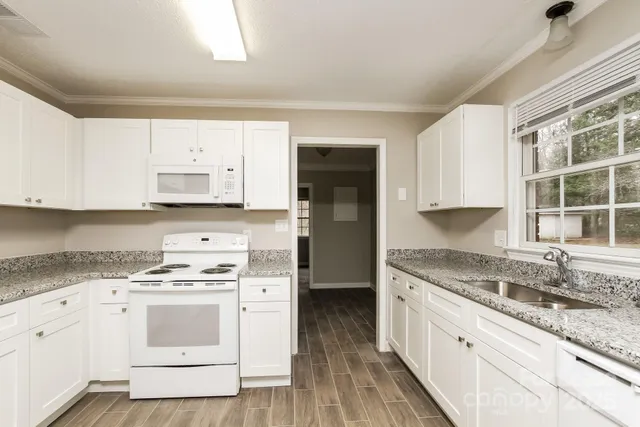 a kitchen with granite countertop white cabinets and white appliances
