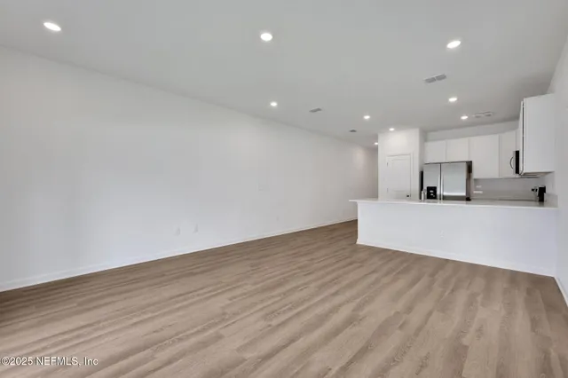 a view of a kitchen with kitchen island wooden floor center island and stainless steel appliances