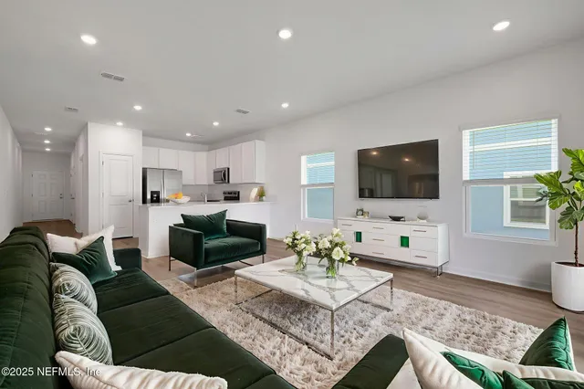 a living room with furniture a flat screen tv and kitchen view