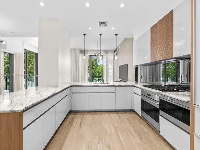 a large white kitchen with stainless steel appliances granite countertop a stove and a sink