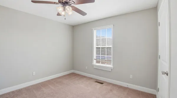 an empty room with a window and a fan