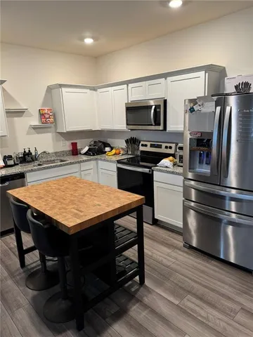 a kitchen with stainless steel appliances kitchen island granite countertop a table chairs stove and refrigerator