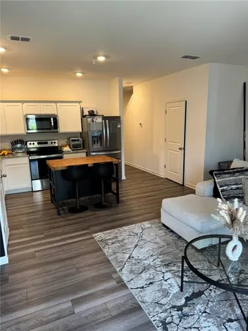 a living room with furniture a flat screen tv and kitchen view